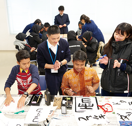 筑波大学附属坂戸高校（埼玉県）でペアとなった高校生に書道を教わるインドネシアの高校生たち